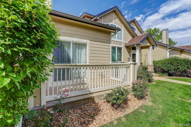 view of side of property featuring covered porch and a lawn