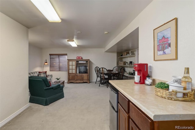 interior space with refrigerator, light carpet, baseboards, light countertops, and brown cabinets