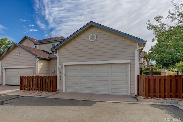 view of front facade featuring driveway, an attached garage, and fence