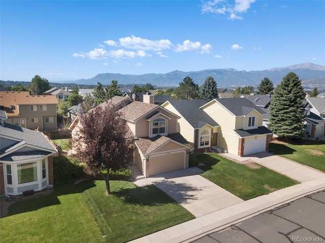 view of front of property featuring a garage, a mountain view, and a front lawn