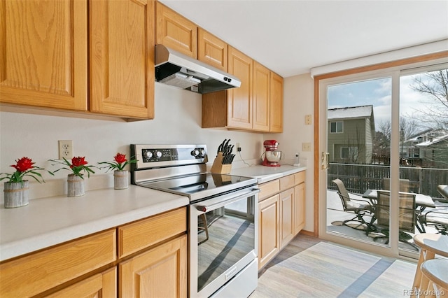 kitchen with stainless steel electric stove, light hardwood / wood-style floors, and light brown cabinets