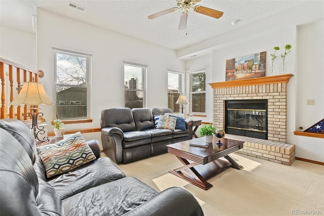 living room with a brick fireplace, a textured ceiling, a healthy amount of sunlight, and carpet