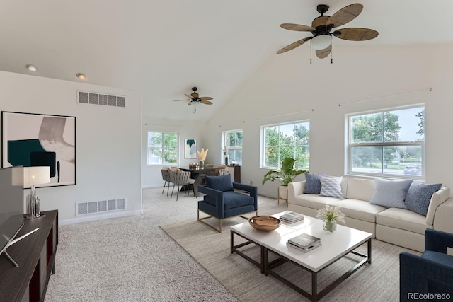 carpeted living room with ceiling fan and high vaulted ceiling