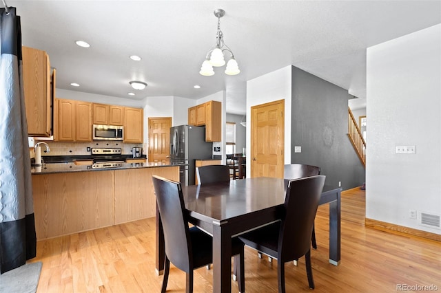 dining space with visible vents, baseboards, stairs, light wood-style floors, and a notable chandelier