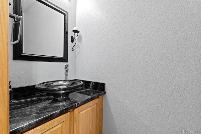 bathroom featuring a textured wall and vanity