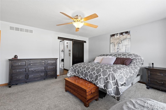 bedroom with light colored carpet, visible vents, a barn door, ceiling fan, and baseboards