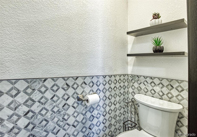 bathroom featuring a textured wall and toilet