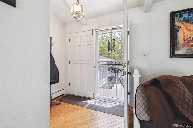 foyer entrance with a baseboard heating unit and wood-type flooring