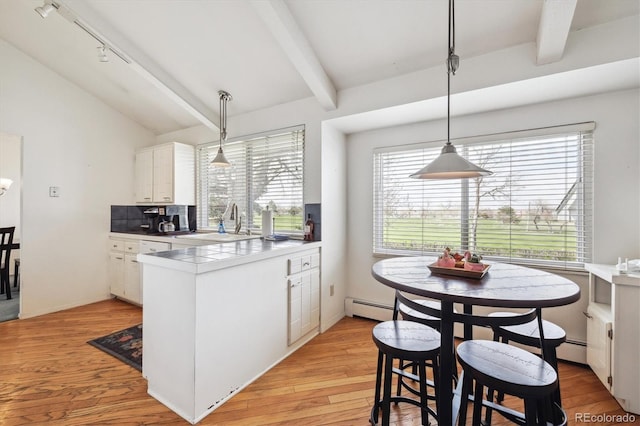 kitchen with a sink, white cabinets, a peninsula, and healthy amount of natural light