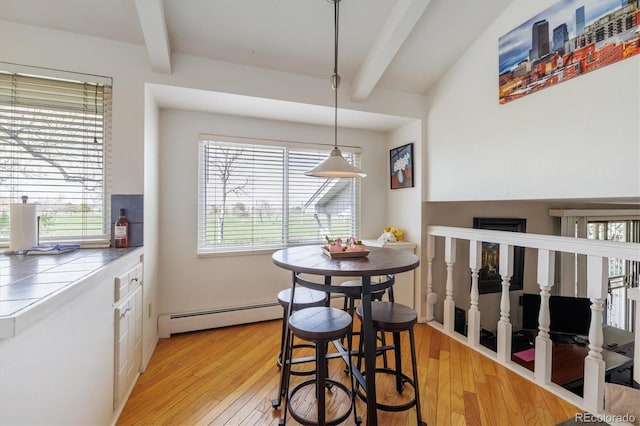 dining room with a baseboard radiator, beamed ceiling, and light wood finished floors