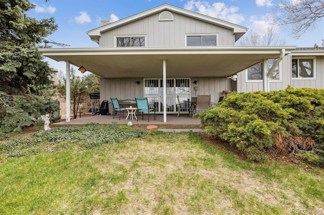 rear view of house featuring a patio, a yard, and a chimney