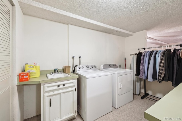 laundry area with washer and dryer, a textured ceiling, cabinet space, and light carpet