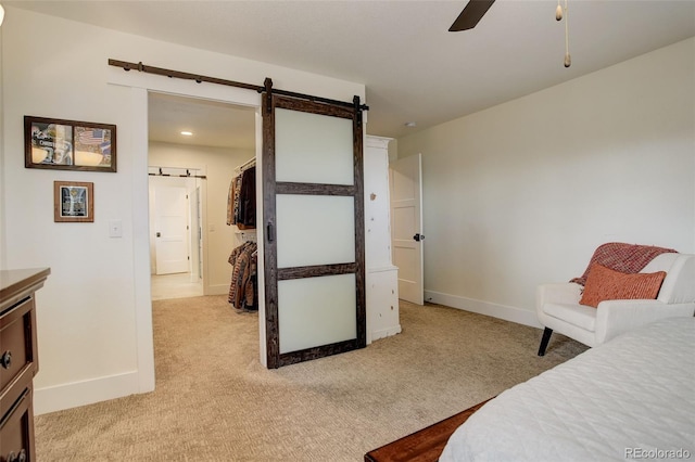 carpeted bedroom with a barn door and ceiling fan