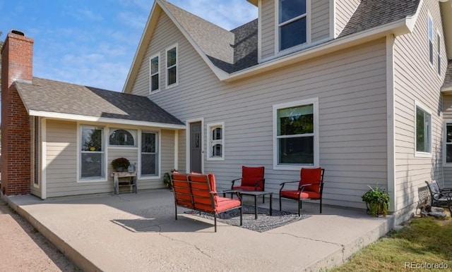 back of property featuring a shingled roof and a patio area