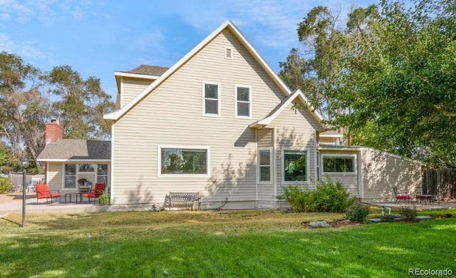 rear view of house with a patio and a lawn