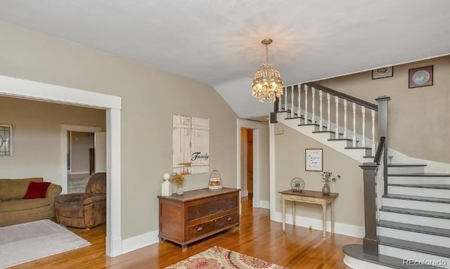 foyer entrance featuring a notable chandelier, stairs, baseboards, and wood finished floors