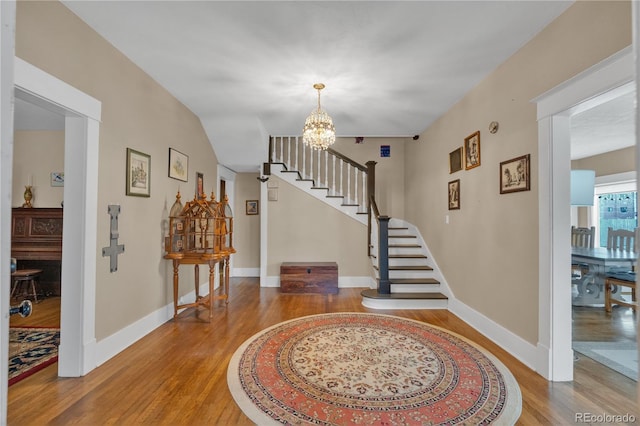 entrance foyer featuring baseboards, stairs, an inviting chandelier, and wood finished floors