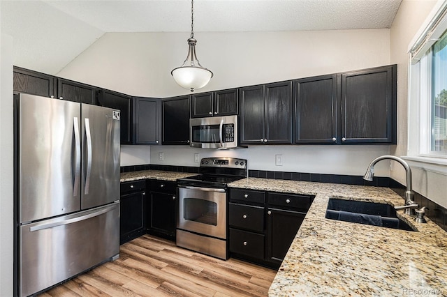 5102 S Lisbon Way, Centennial, CO 80015 - kitchen featuring appliances with stainless steel finishes, lofted ceiling, dark cabinets, decorative light fixtures, and light wood-type flooring