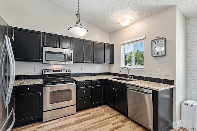 5102 S Lisbon Way, Centennial, CO 80015 - kitchen featuring stainless steel appliances, dark cabinetry, a textured ceiling, light wood-style floors, and lofted ceiling