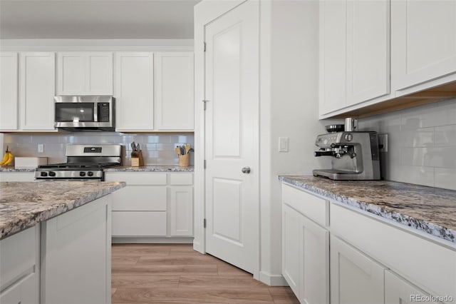 8372 Bijou Creek Ave, Littleton, CO 80125 - kitchen featuring appliances with stainless steel finishes, tasteful backsplash, white cabinetry, and light stone countertops