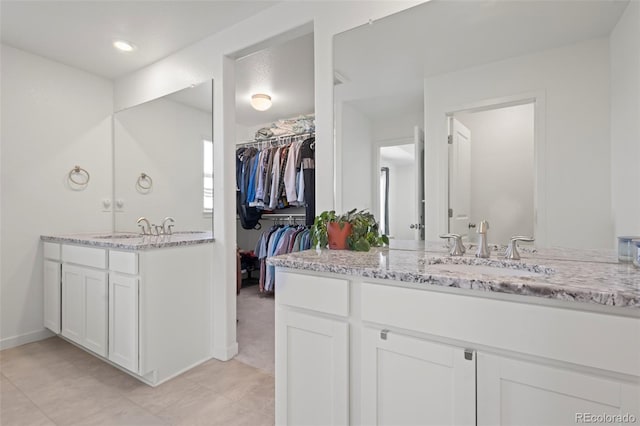 8372 Bijou Creek Ave, Littleton, CO 80125 - bathroom featuring two vanities, a spacious closet, tile patterned floors, and baseboards