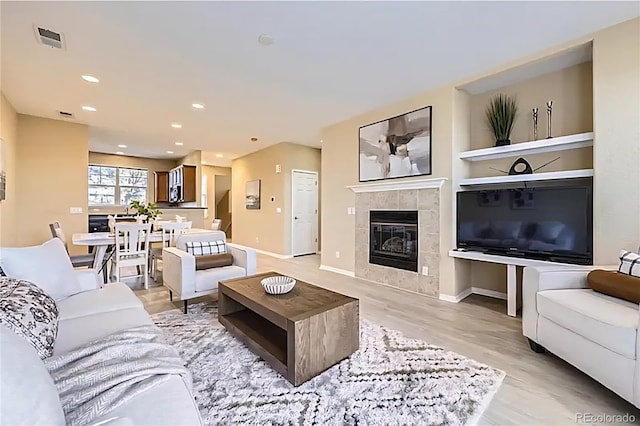 8915 Federal Blvd Unit 203, Westminster, CO 80260 - living room featuring a tile fireplace, built in shelves, recessed lighting, baseboards, and light wood finished floors