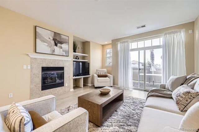 8915 Federal Blvd Unit 203, Westminster, CO 80260 - living room featuring healthy amount of natural light, wood finished floors, a tile fireplace, and built in shelves