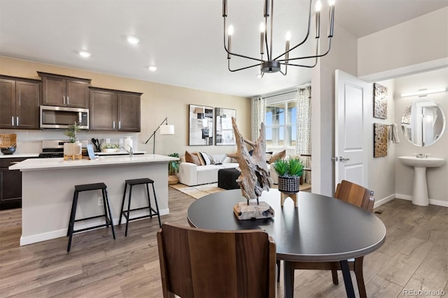 dining space with light wood-style floors, a chandelier, baseboards, and recessed lighting