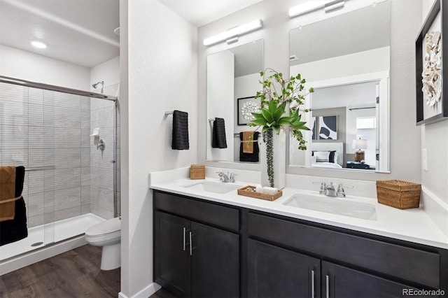 full bathroom featuring a stall shower, toilet, wood finished floors, and double vanity