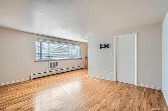 empty room featuring baseboard heating and light hardwood / wood-style flooring