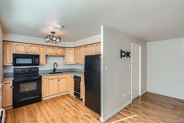 kitchen with a sink, black appliances, light wood-style flooring, and light brown cabinets