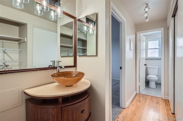 bathroom featuring track lighting, toilet, wood finished floors, and vanity