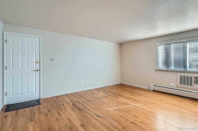 empty room with baseboards, light wood-type flooring, and baseboard heating