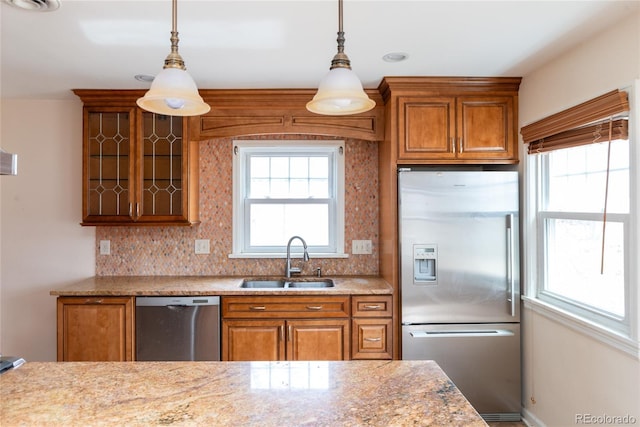 kitchen featuring brown cabinetry, appliances with stainless steel finishes, a wealth of natural light, and a sink