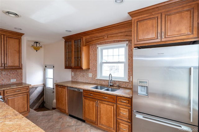 kitchen with brown cabinetry, visible vents, a sink, decorative backsplash, and stainless steel appliances