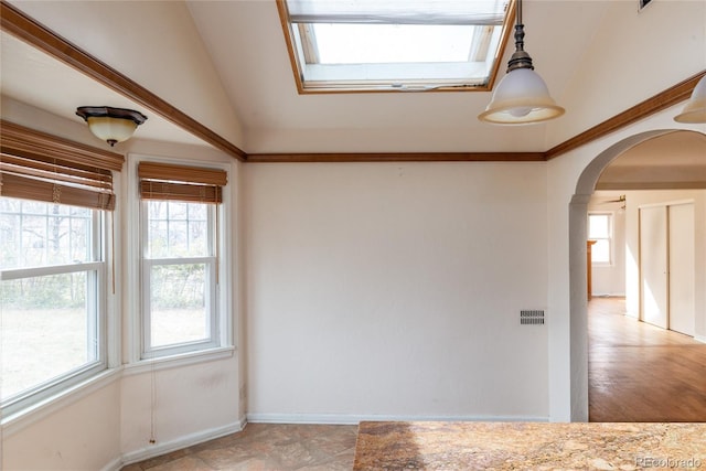 spare room with lofted ceiling with skylight, baseboards, and arched walkways