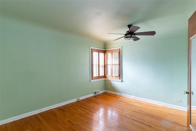 unfurnished room with baseboards, wood finished floors, visible vents, and ceiling fan