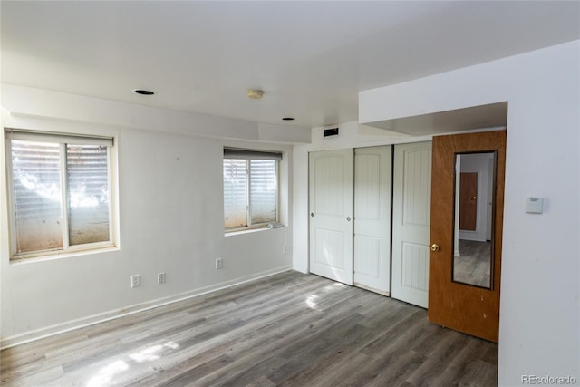 unfurnished bedroom with visible vents, wood finished floors, a closet, and baseboards