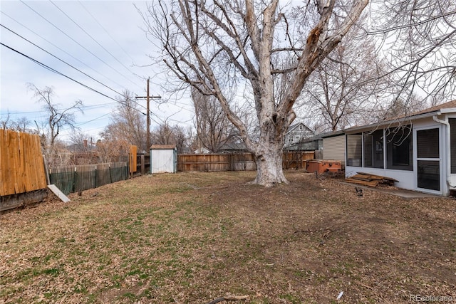 view of yard with a shed, an outdoor structure, a fenced backyard, and a sunroom