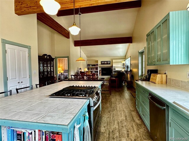 kitchen with beam ceiling, tile countertops, stainless steel appliances, and green cabinets