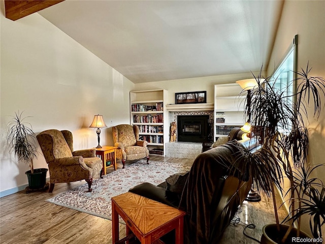 living room with vaulted ceiling with beams, a tile fireplace, and light hardwood / wood-style flooring