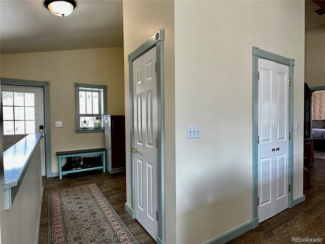 corridor with dark wood-type flooring and vaulted ceiling