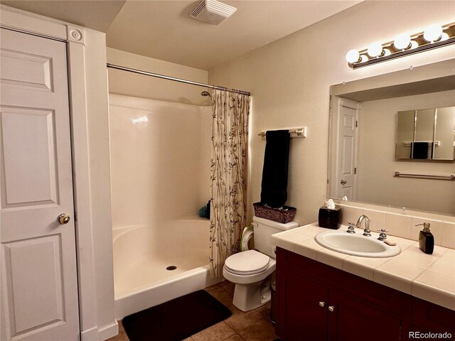 bathroom with a shower with shower curtain, vanity, toilet, and tile patterned flooring