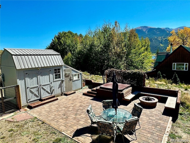 view of patio featuring a mountain view, a shed, and an outdoor fire pit