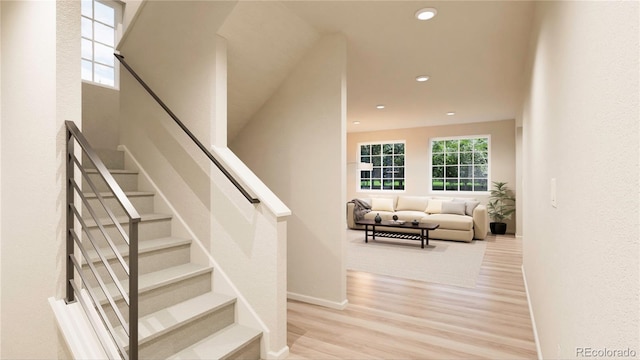 stairs featuring plenty of natural light and hardwood / wood-style flooring