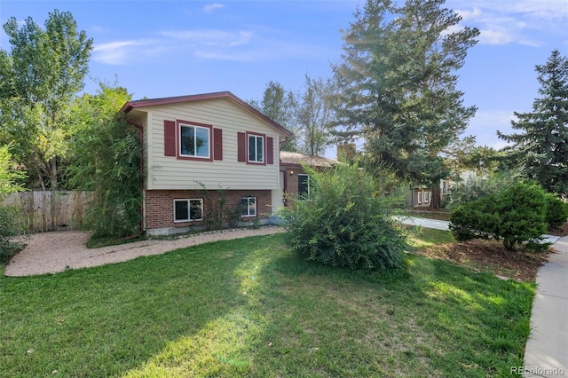 view of front of property with brick siding, fence, and a front lawn