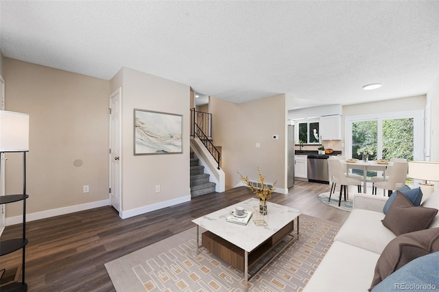 living room featuring baseboards, stairway, a textured ceiling, and wood finished floors