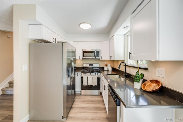 kitchen with dark countertops, appliances with stainless steel finishes, white cabinets, and a sink