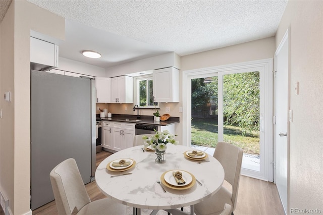 dining area featuring light wood-type flooring and a textured ceiling