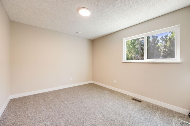 carpeted empty room featuring visible vents, a textured ceiling, and baseboards